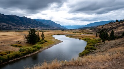 Scenic Landscape with River Flowing Through Meadow, Mountains and Cloudy Sky in Autumnal Setting