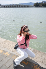Woman sitting on park relaxing at lake view of Summer Palace in Beijing, China.
