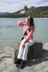 Woman sitting on park relaxing at lake view of Summer Palace in Beijing, China.
