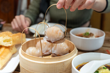 Hand holding dim sum called Hakau, dumplings made from shrimp and meat is a traditional Chinese...