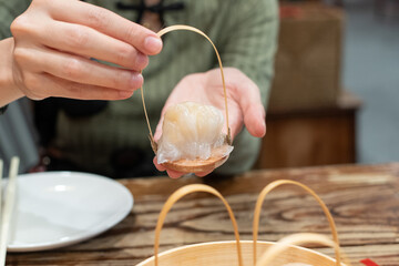Hand holding dim sum called Hakau, dumplings made from shrimp and meat is a traditional Chinese...