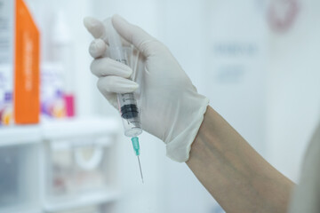 Doctor filling syringe with medication from vial on blurred background.