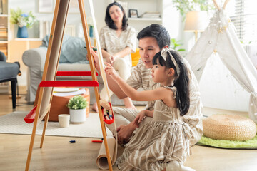 Happy Asian family spending quality time together at home. Father and daughter drawing on the floor...