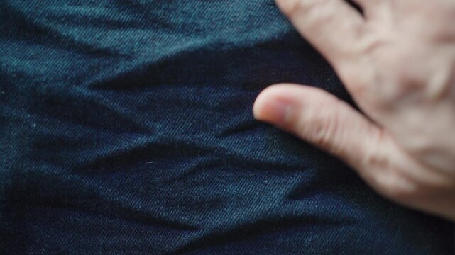 Men hand touching wrinkles on jeans