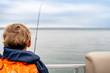 Youth caucasian boy looking out over a body of water while fishing 