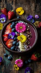 Colorful fruit and flower decorated smoothie bowl on a rustic wooden surface.
