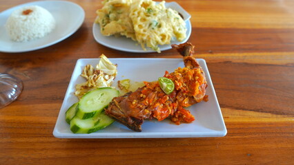 Delicious Indonesian Meal of Fried Chicken, Rice, and Vegetables on a Wooden Table