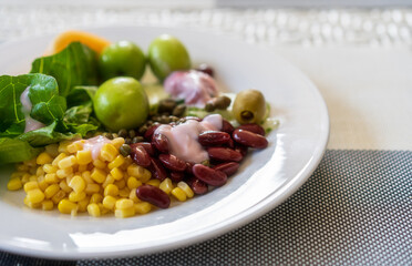 fruits vegetable salad mixed with sweetcorn red beans greens jujube and strawberry yogurt or salad dressing in white plate for diet juicy cuisine and vitamins or vegan food nutrition with copyspace
