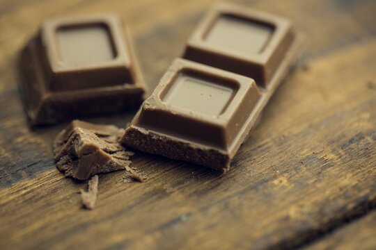 Naklejki Flat design milk chocolate squares are resting on wooden surface with scattered shavings and crumbs