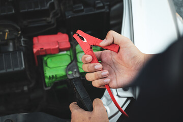 Car mechanic holding booster cables for jump start car for empty battery dead and low power problem...