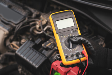 Mechanic uses electrical meter to check battery low energy problem for car care service maintenance and re charger or jump start or change battery replacement.