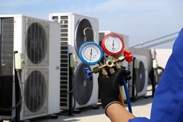 Air conditioning electrical technician service using measuring manifold gauge checking HVAC condition system and refrigerant filling air conditioner after cleaning and maintenance compressor units.