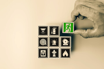 Hand chooses door exit sing on wooden toy block stack for fire escape to prevent with fire extinguisher and emergency prevention protection symbol for safety first and rescue and training concepts.