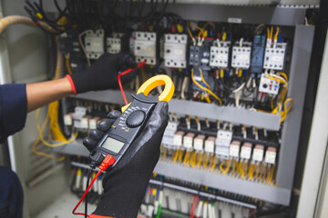 Electrical service technician use electricity measuring tools equipment checking electric current circuit breaker terminal panel and cable wiring main power distribution board for maintenance system.
