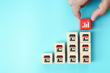 Hand choose wooden block stack with graph and franchise icon for goal to growth is investment planning financial and branch expansion and management bank loans or marketing franchising business.