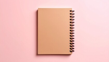 Spiral notebook with kraft paper cover placed on pink pastel background representing back to school and stationery themes