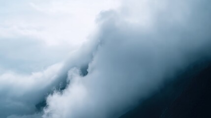 Obraz premium Dramatic clouds enveloping mountain peaks create a moody atmosphere, showcasing the beauty of nature's elements and the interplay of light and shadow in the landscape