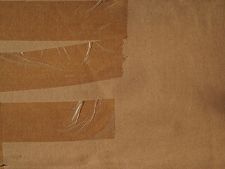 The surface of a kraft brown cardboard box with tape and staples
