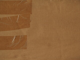 The surface of a kraft brown cardboard box with tape and staples