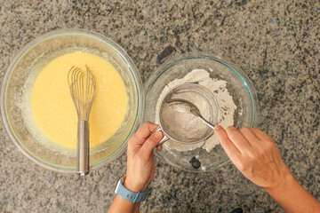 Overhead View of Hands Sifting Flour with Hand Crank Sifter for Baking