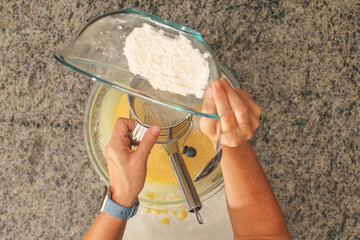 Overhead View of Hands Sifting Flour with Hand Crank Sifter for Baking