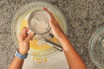 Overhead View of Hands Sifting Flour with Hand Crank Sifter for Baking