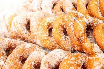 Doughnuts rows powdered with coarse crystal sugar, soft focus close up side view