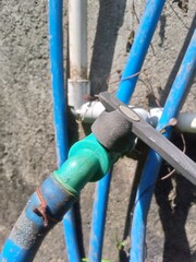 A close-up shot of a metal water faucet with a garden hose attached, ready for use.