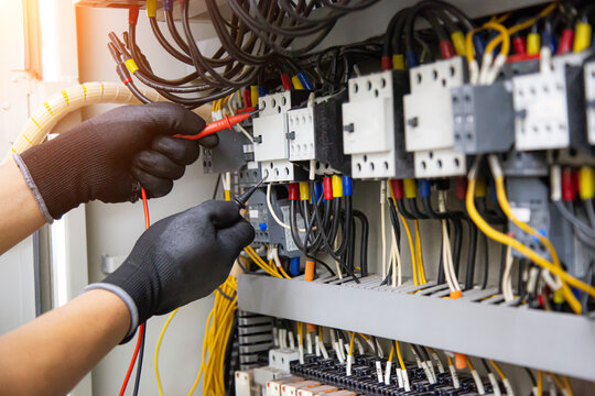 Electrical technician hand checking electricity circuit breaker main power on switchboard cabinet for service maintenance and electric cable wiring check for safety concepts.