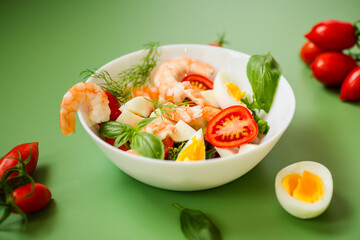 Delicious seafood salad with egg and basil on a green background