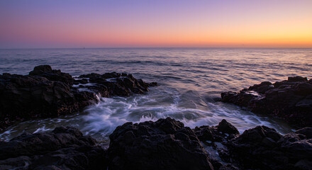 Obraz premium Twilight Ocean Waves Crashing on Rocky Shore