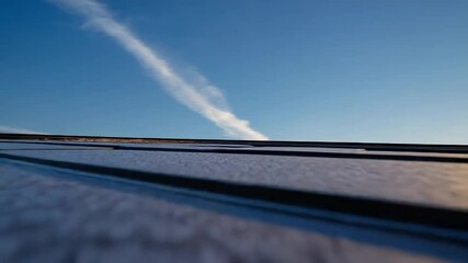 Rooftop covered with snow at sunset with contrails in the sky - Powered by Adobe
