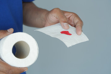 Person holding toilet paper with red stain in close-up