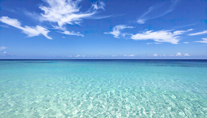 Fototapeta premium Clear turquoise ocean water under blue sky with wispy clouds on sunny day