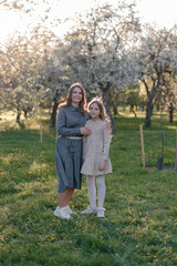 Fototapeta premium A young mother hugs her child in the park. Happy family, mom and daughter, walking in the park