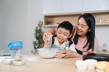 Family Cooking Together. A happy mother guiding her son in mixing ingredients during their kitchen...