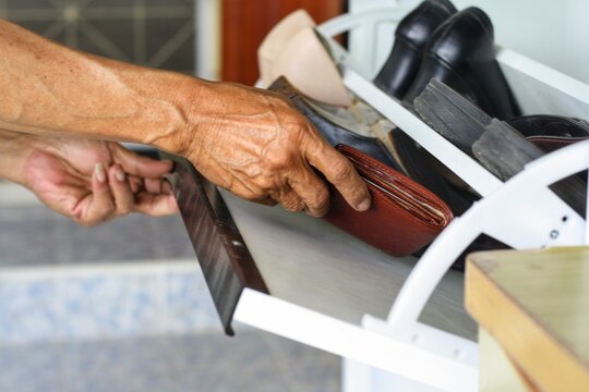 Elderly man is keeping wallet in shoes cabinet because dementia or Alzheimer's disease.Memory loss and behavior change are major symptom of disease make a trouble for senior person.Healthcare concept.