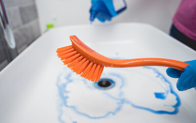 Young housewife diligently scrubs and cleans the sink in bathroom