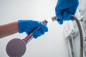 Woman's hands in gloves connecting the hose to a shower head