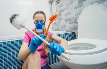 Young housewife diligently scrubs and cleans the toilet bowl in bathroom