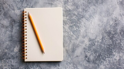 Minimalist composition of notepad and pencil on textured gray surface