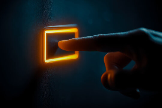 Person pressing illuminated power button on dark wall