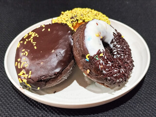 Three delicious donuts topped with sprinkles and various colored glazes, displaying a tempting...