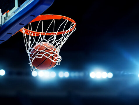 Orange basketball swishing through net with stadium lights hoop scoring