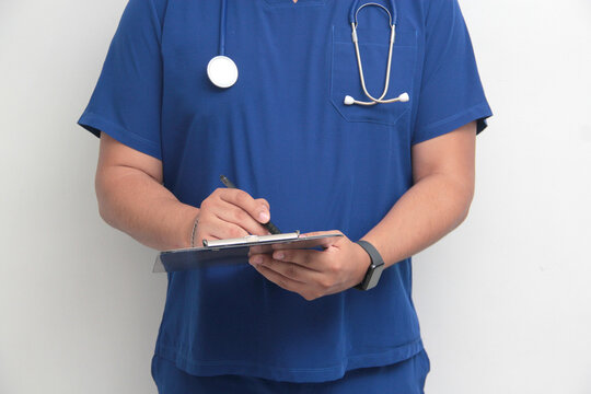 Dark-skinned Latino male specialist doctor reviews and writes patient reports on clipboard for record keeping and follow-up