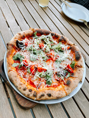 Freshly made pizza topped with vegetables and cheese at an outdoor table setting