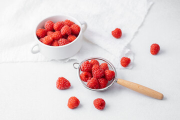 Raspberries in and around strainer on marble for recipe prep or organic diet concept