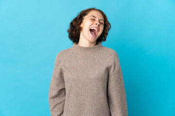 Young English woman isolated on blue background laughing