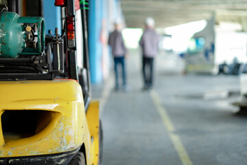 Blur Young and senior warehouse workers walk through a loading zone surrounded by cargo trucks. Background shows organized freight lines and operational warehouse flow.