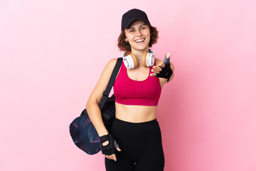 Young sport woman with sport bag over isolated background shaking hands for closing a good deal